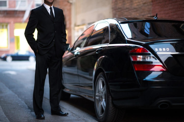 Image of a buisnessman next to a black car